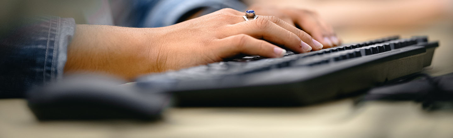 Closeup of hands on a keyboard.