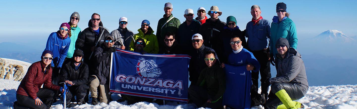 Gonzaga Students holding up Gonzaga flag at the top of Mt Adams posing for a group photo
