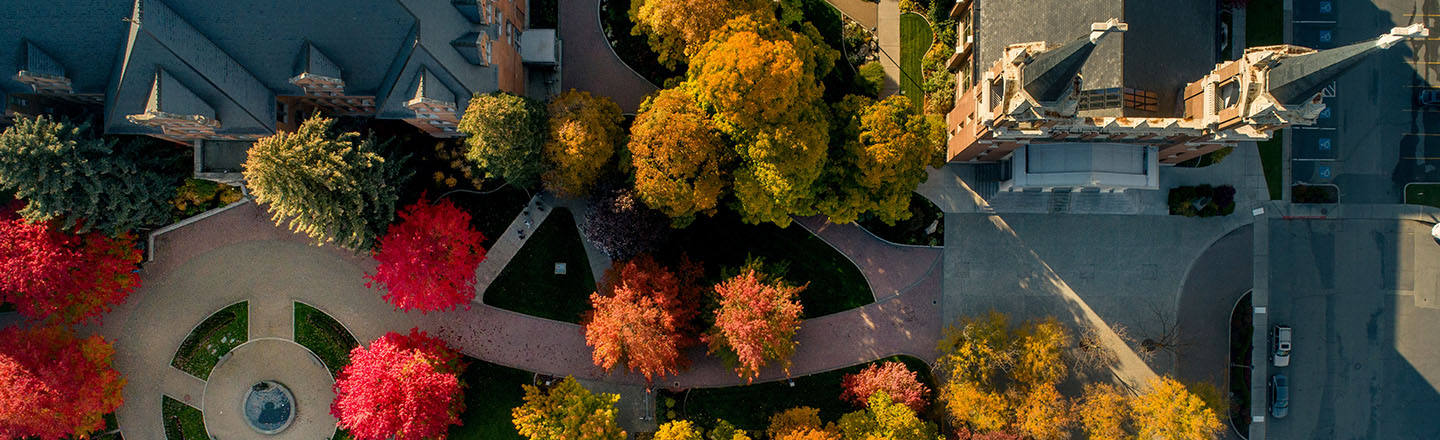 Looking down from a drone over College hall with fall colored red, orange and yellow leaves.