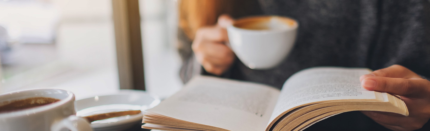 A woman holding coffee and a book