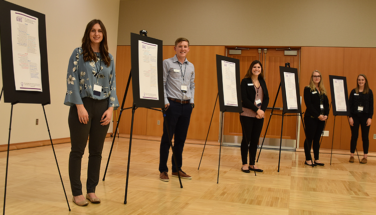 students stand next to 5 posters displaying the history of the Gonzaga Institute for Hate Studies