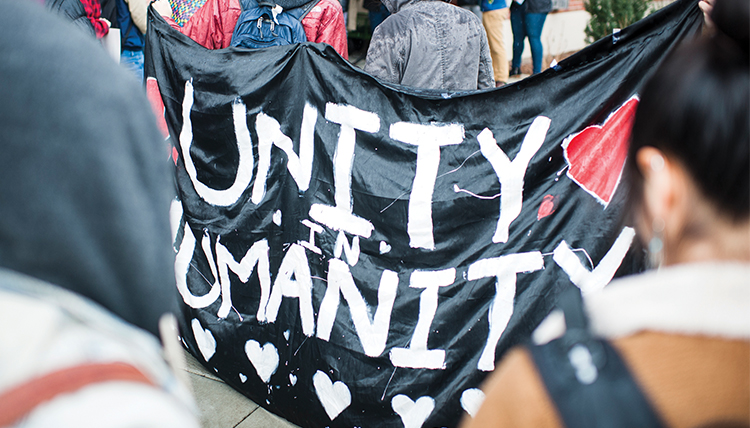 students gather to support people of color, hold sign says diversity in humanity