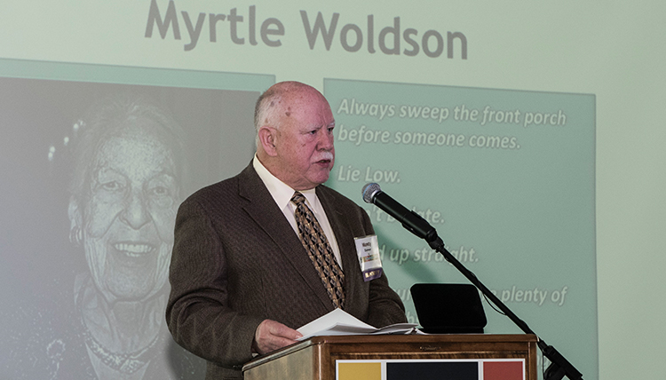 Monty Danner at podium with photo of Miss Woldson on screen behind