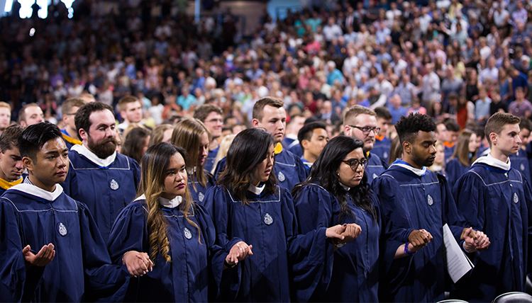 graduates hold hands in prayer
