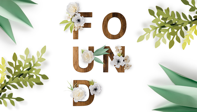 Wooden letters spelling 'Found' framed by paper flowers and leaves