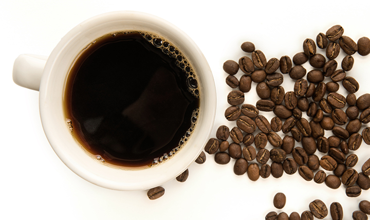 A cup of black coffee is shown alongside coffee beans. 