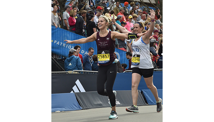 Lauren Zeutenhorst crossing finish line at Boston Marathon, arms spread wide