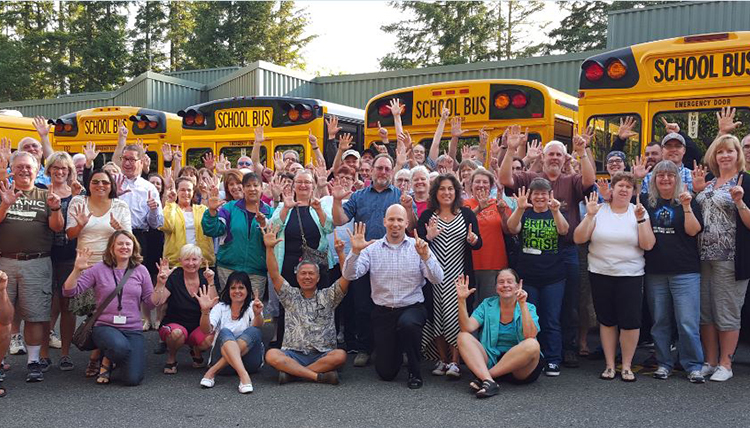 Group of educators in front of busses, cheering