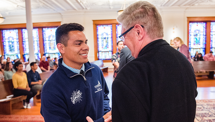 father pat lee congratulates student in chapel