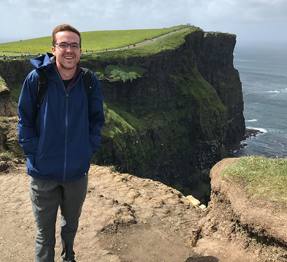 Konner Sauve stands on a cliff overlooking the sea in Ireland. 