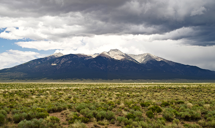 Little Bear Peak is seen with storm clouds surrounding the summit. 