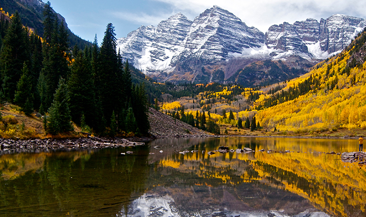 The Maroon Bells peaks are seen surrounded by fall colors. 