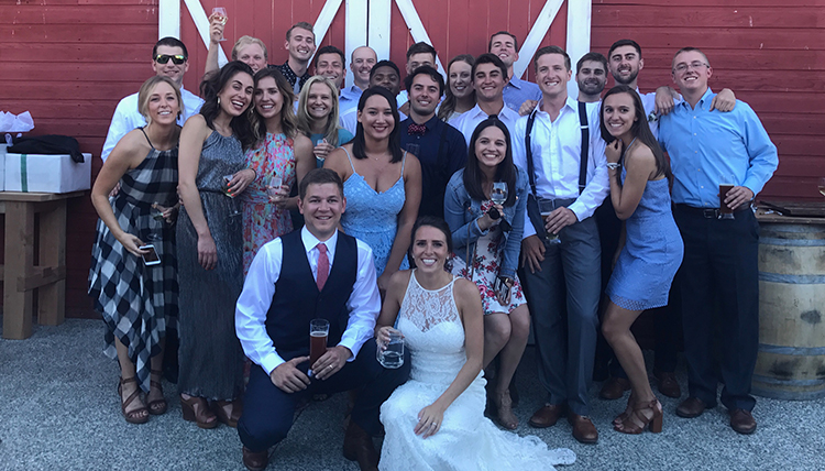 couple surrounded by friends in front of barn