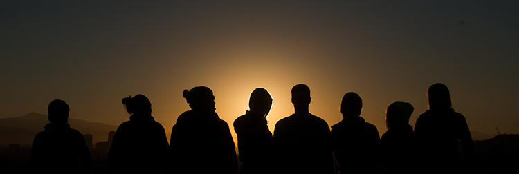 A group of students are silhouetted against the sunset