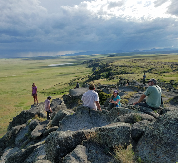 students stand and sit atop rocks in the Montana wilderness