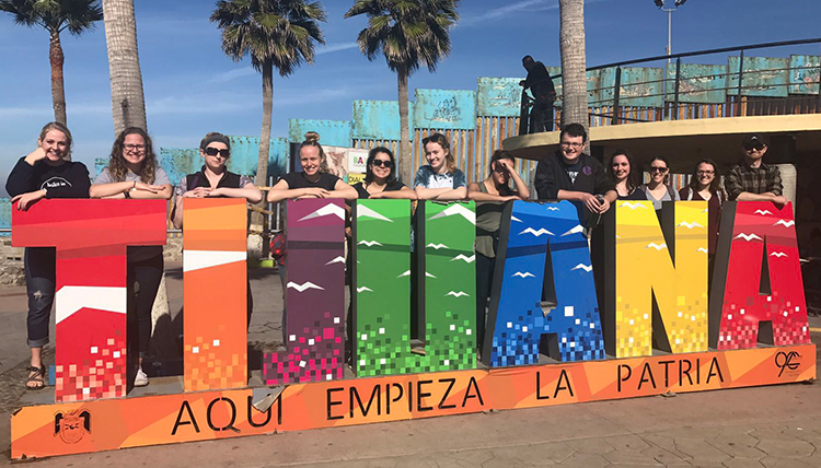 Gonzaga students pose at colorful Tijuana sign on the beach in Mexico
