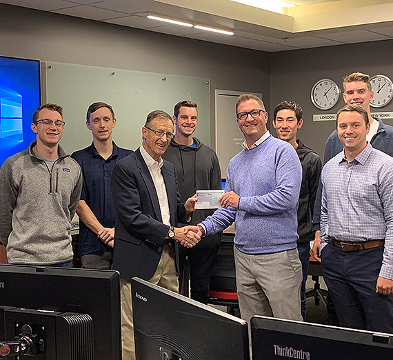 Students in Professor Bud Barnes' current investment class receive the check on behalf of the 2017-18 class, which won the award. Michael Jackson, branch manager for D.A. Davidson’s Spokane office, presents the check to Barnes. GU photo  