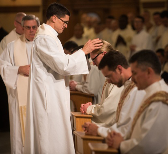 A priest offers blessings to newly ordained Jesuits. 