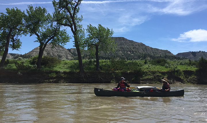Two people paddle a canoe down the Missouri River