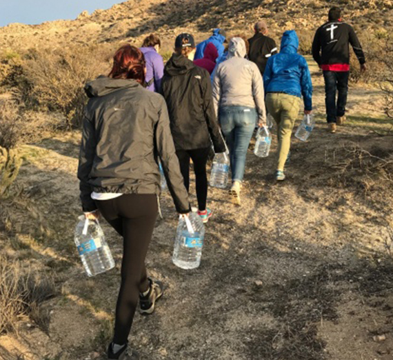 Students carry water jugs through the desert near the Mexico-US border.  