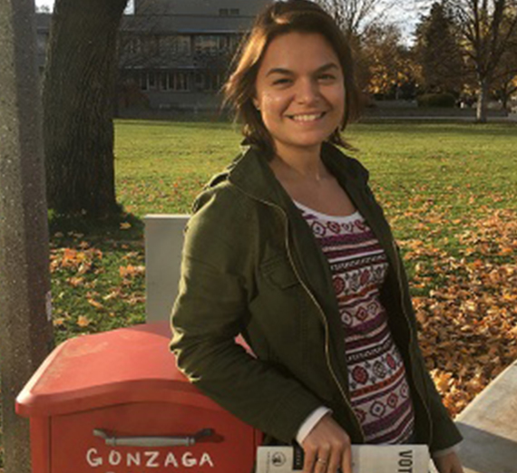 Student Sidnee Grubb stands next to a mailbox holding a ballot. 