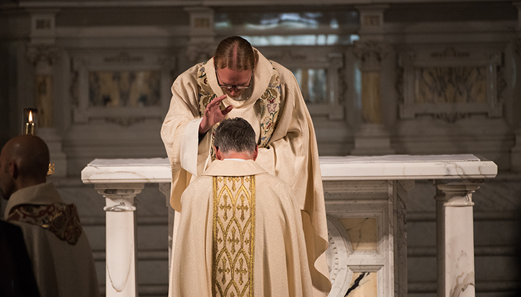 One Jesuit priest prays over a new Jesuit priest in ceremony at St. Aloysius