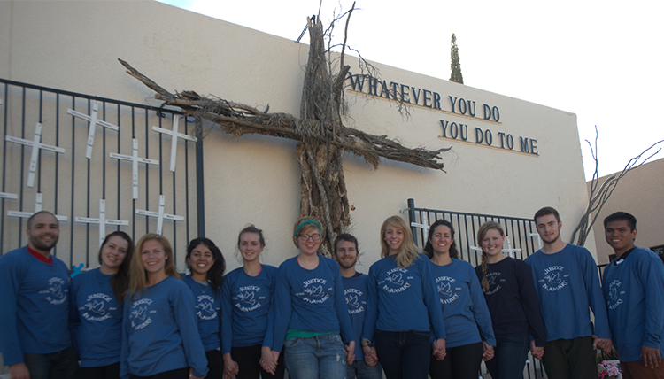 The author (center) is shown with his Justice in January group beneath a cross and the words 'whatever you do, you do to me.'