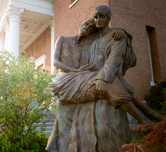 A statue of St. Aloysius Gonzaga holding an infirm person on Gonzaga University campus.