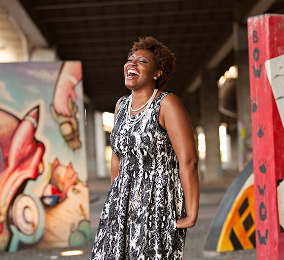 African-American woman standing around colorful pieces of art and laughing