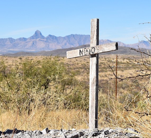 a cross in the desert reads "ninos"