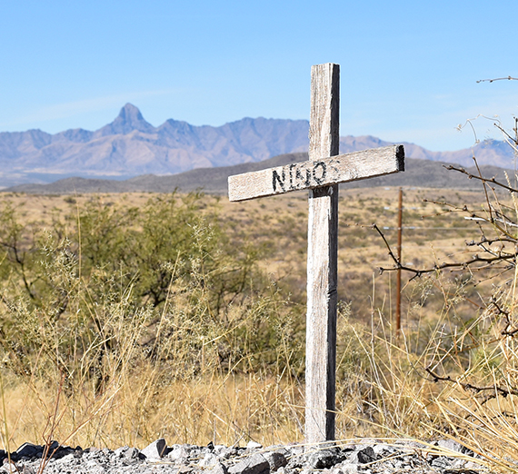 a cross in the desert reads "ninos" 