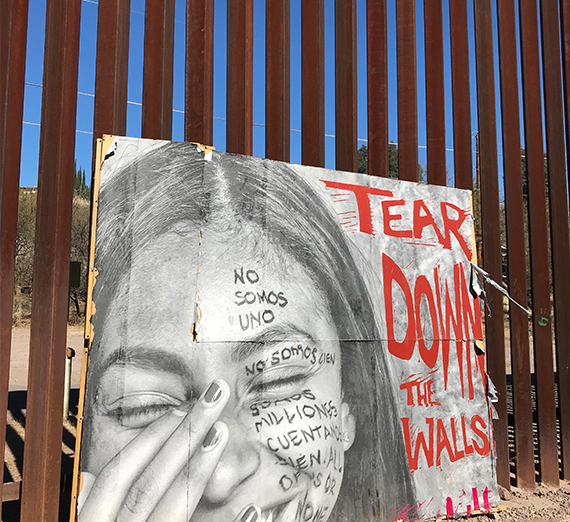 a sign at the wall separating Mexico from the U.S. reads "tear down the walls" 