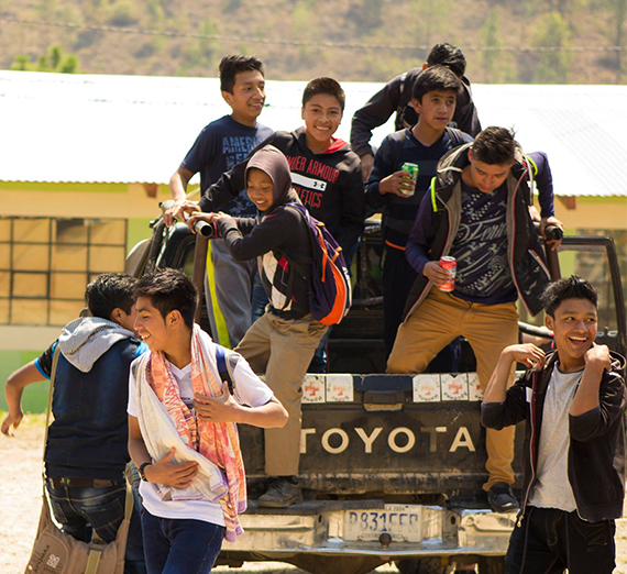 Smiling Guatemalan children climb out of the back of a Toyota pickup 