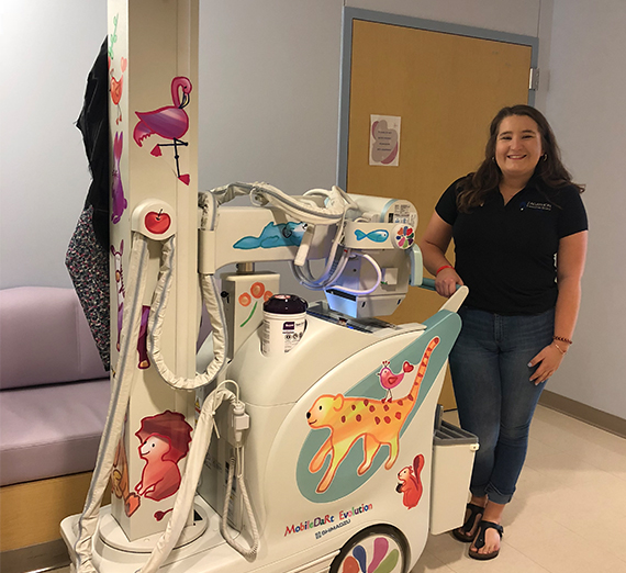 Lauren Tham stands next to the infant x-ray machine in the NICU. 