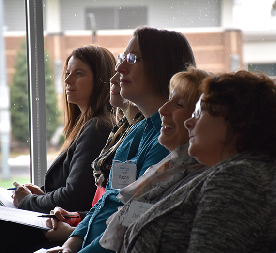 5 women sit at conference smiling