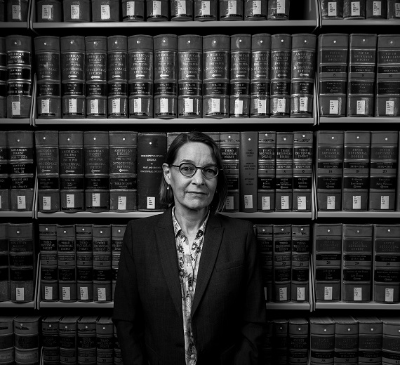 Megan Ballard stands in front of a large bookcase.