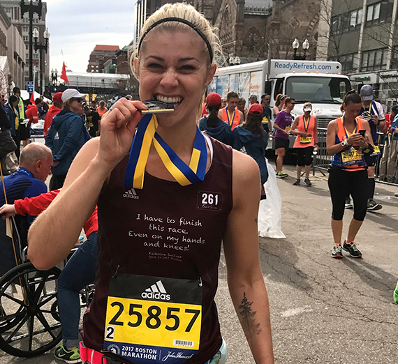 Lauren Zeutenhorst bites medal after finishing Boston Marathon