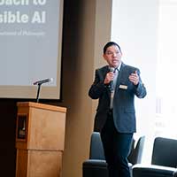 Jay Yang speaking on a stage near a podium.