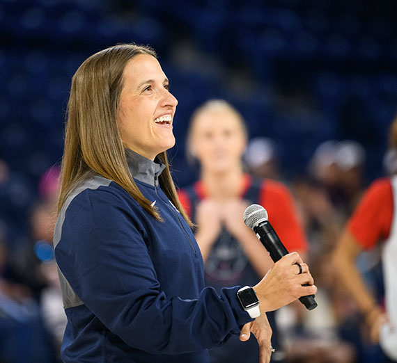 Lisa Fortier holds a microphone in her hand and is smiling.