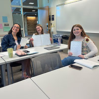 Three students in a classroom setting.