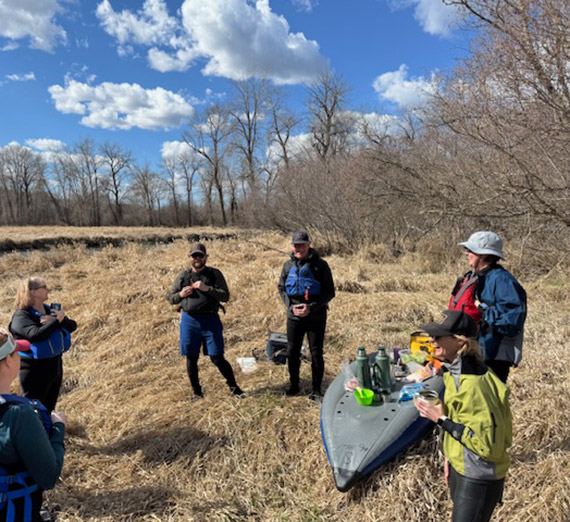 a group of faculty standing in a brown field with blue sky