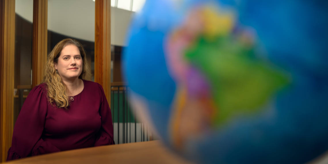 Associate Dean Stacy Taninchev poses in background, on third floor of the Hemmingson Center, with globe in the foreground.