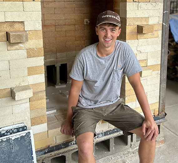Owen Nichols sitting in front of a brick kiln.