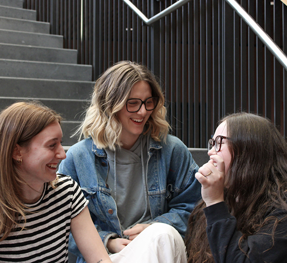 3 female GUSR seniors laughing on the stairs together