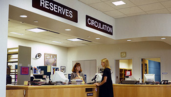 A staff member helps a patron at the circulation desk