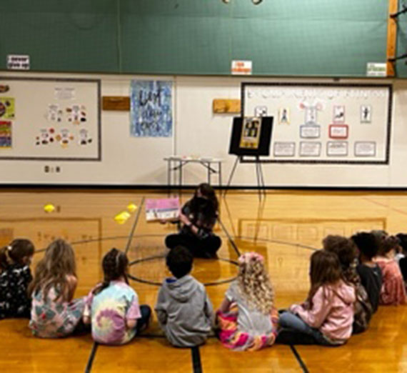 Librarian Candise Branum reading to a group of children with their backs to the camera
