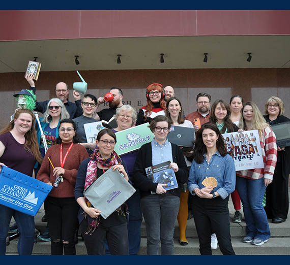 Faculty and staff of Foley Library on the front steps of Foley holding library items, books, bins, computers