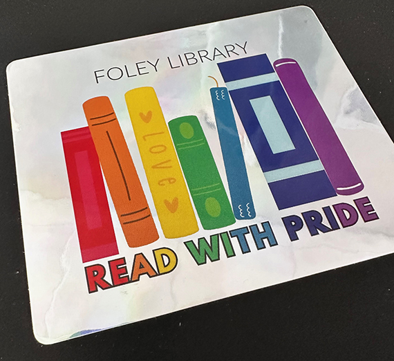 Metalic sticker with rainbow of books reading Foley Library Read with Pride