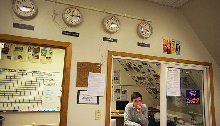 A students leans against a window in the GU Student Media office.