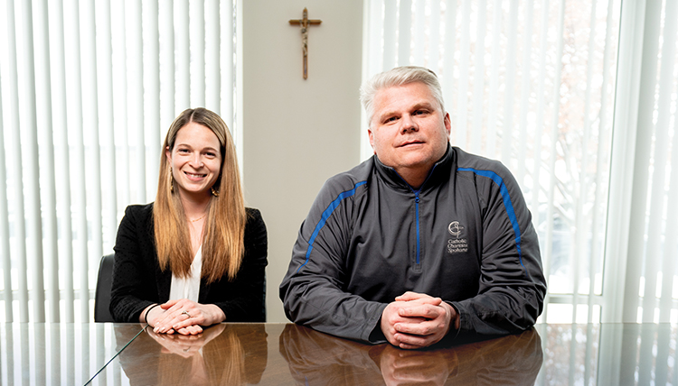 Sarah Yerden and Rob McCann, two executives at Catholic Charities, sit at a table.